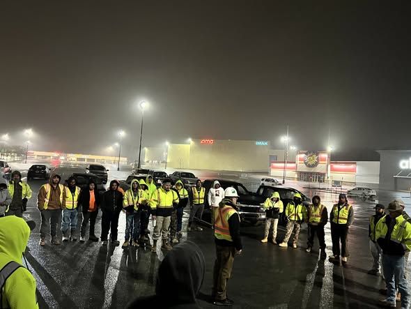 Under dark skies and steady rain, crews on the I-75/I-24 project in Chattanooga gather for their morning safety meeting.