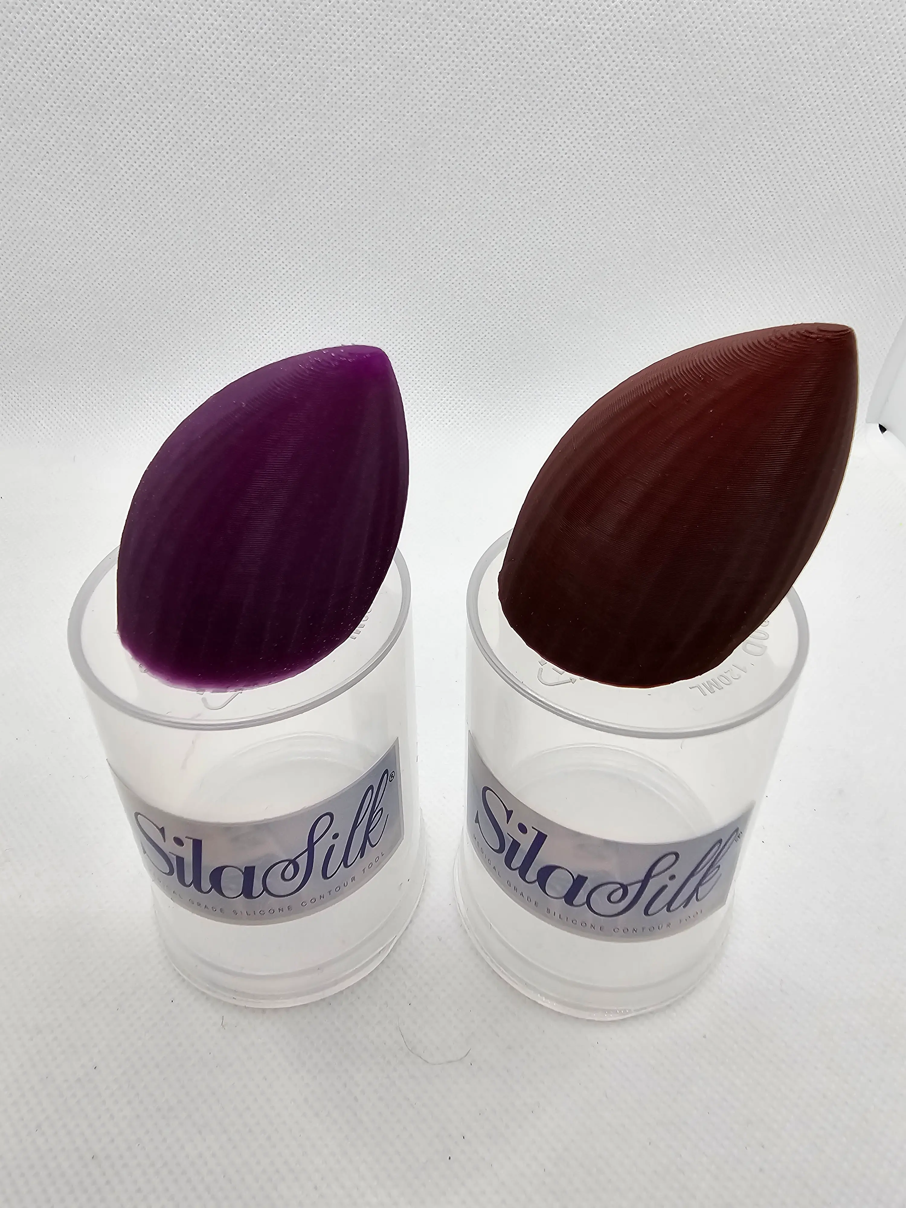 Two SilaSilk applicators, one burgundy and one purple, in their packaging