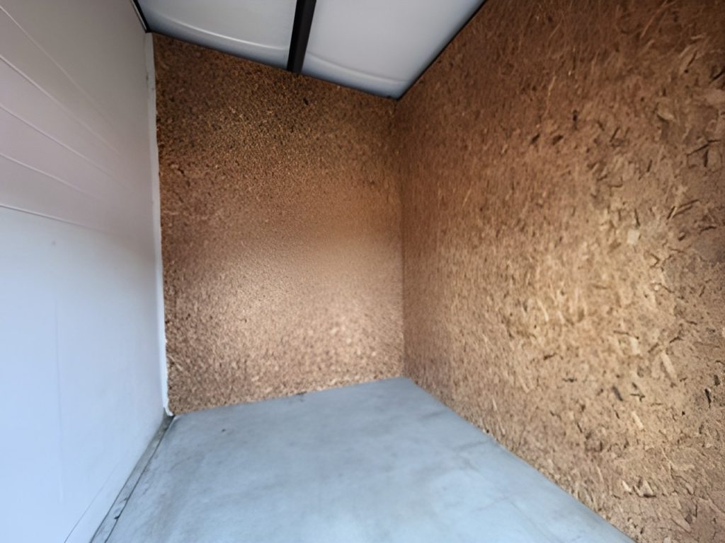 Interior of a 10x12 storage unit with wood-panel walls and concrete floor